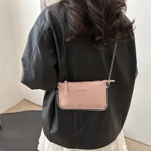 Pink envelope crossbody bag with silver rivet details and chain strap shown on model