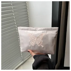 Dettaglio della borsa da trucco in raso rosa con ricamo a farfalla di alta qualità