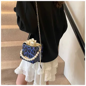 Close-up of blue leopard print mini bucket bag with pearl handle and gold chain strap