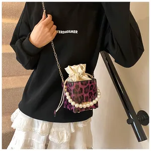 Detail of purple leopard bucket bag with large pearl handle and gold chain strap