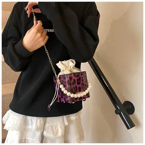 Detail of purple leopard print bucket bag with pearl handle and golden chain strap