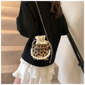 Detail of leopard print bucket bag with pearl handle, chain strap, and drawstring closure
