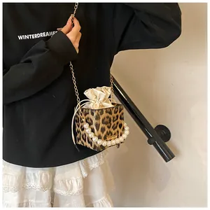 Detail of leopard print bucket bag with pearl handle and golden chain strap for women