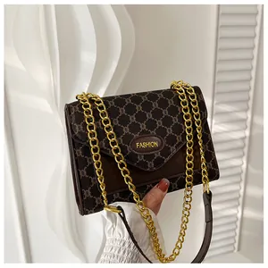 Détail du sac bandoulière vintage marron avec motif monogramme et chaîne dorée