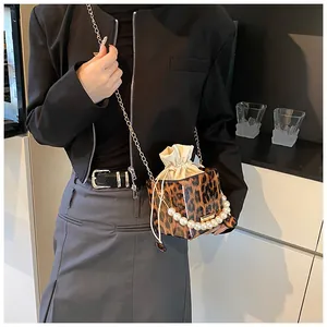Detail of leopard print cube bucket bag featuring pearl handle and drawstring lining