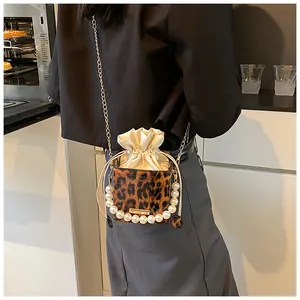 Detail of leopard print bucket bag with pearl handle and golden chain strap