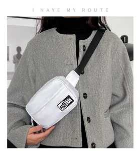Close-up of white minimalist crossbody bag with FASHION label on grey wool coat