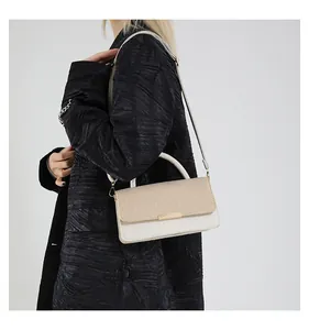 Détail d'un sac bandoulière crème chic avec boucle dorée et poignée sur mannequin