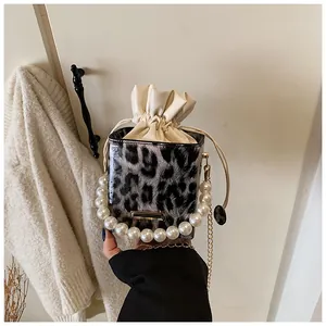 Detail of leopard print bucket bag featuring large pearl handle and metal chain strap