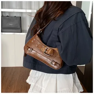Brown PU leather underarm bag with metal eyelets and buckles shown on shoulder