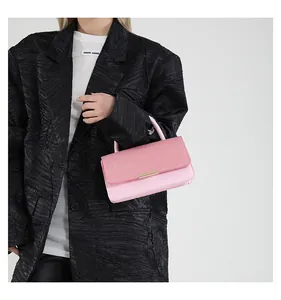 Détail d'un sac bandoulière rose avec rabat tissé et boucle en métal doré élégante