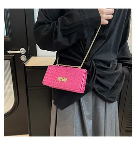 Macro detail of bright pink crocodile pattern leather bag with golden chain and clasp