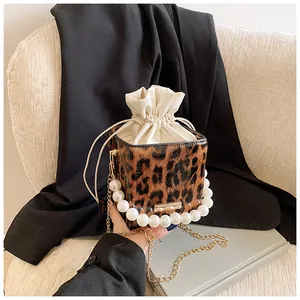 Detail of leopard print bucket bag with pearl handle and golden chain strap
