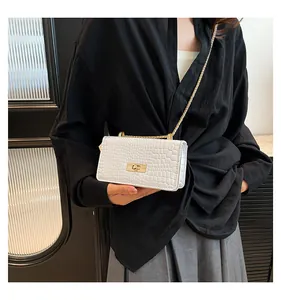Detailed view of white crocodile pattern crossbody bag with gold chain strap on a model