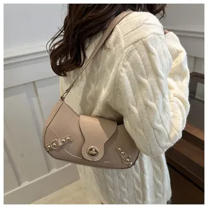 Detailed side view of a cream crescent bag with gold rivets and metallic lock