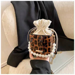 Detail of leopard print bucket bag with elegant pearl handle and gold chain strap