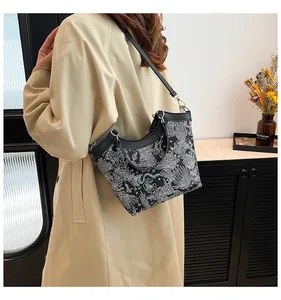 Detail of elegant floral silk embroidery on a black bucket bag with leather shoulder strap