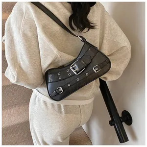 Close-up of black punk style shoulder bag with metallic buckle and eyelet details