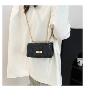 Detail of black patent leather crossbody bag with crocodile pattern and gold chain strap