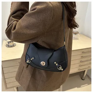 Detailed view of black crescent shoulder bag with golden metal twist lock and stud details