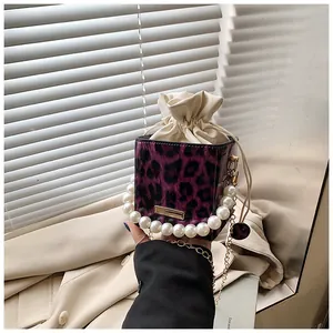 Detail of purple leopard bucket bag with pearl handle and golden chain in natural light