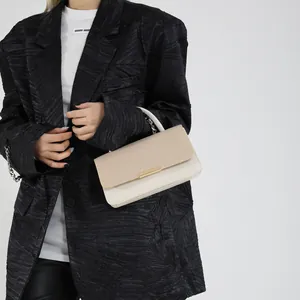 Sac bandoulière beige chic avec rabat tissé et fermoir doré porté par un mannequin