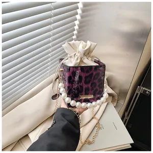 Detail of purple leopard print bucket bag with pearl handle and golden chain strap