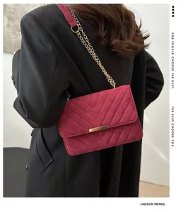 Detail of burgundy suede chain bag showing V-shape quilting and gold metal buckle