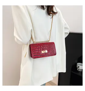 Close-up of red crocodile pattern patent leather bag with a gold chain strap