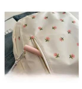 Detailed shot of floral white backpack front pocket showing cosmetic storage capacity