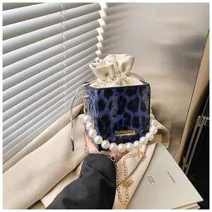 Detail of blue leopard print bucket bag with pearl handle and golden chain strap