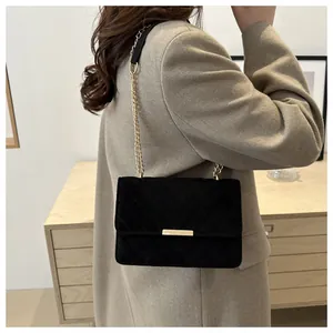 Close-up of black suede chain bag featuring V-shaped quilted texture and gold metal buckle