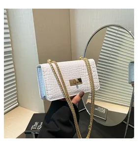 Detail of white crocodile pattern square bag with gold metal buckle and chain strap