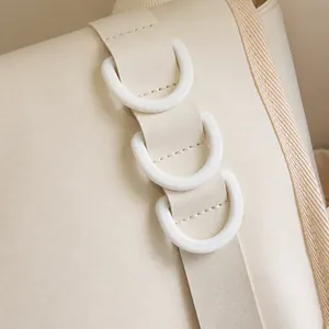 Détail d'une bandoulière de sac crème avec trois anneaux fonctionnels en résine D