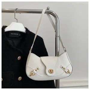 Detail of white glossy crescent bag with gold oval twist lock and rivet accents