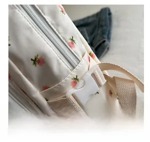 Close-up of white nylon backpack featuring strawberry prints and a sturdy plastic buckle