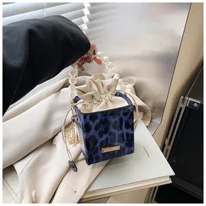 Detail of blue leopard print bucket bag with large faux pearl handle and drawstring inner