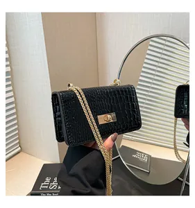 Close-up of black crocodile pattern leather bag with golden chain strap and metal lock