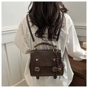 Detailansicht des braunen Lederrucksacks mit Metallschnalle und Logo im Vintage-Stil