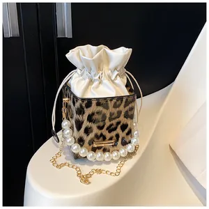 Detail of leopard print bucket bag with pearl handle and gold chain shoulder strap