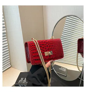 Detail of red crocodile pattern patent leather box bag with gold metal clasp and chain