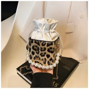 Detail of leopard print bucket bag featuring pearl handle and gold chain strap
