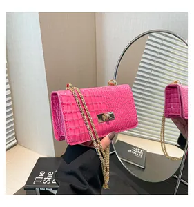 Detailed view of pink croc-embossed patent leather bag with gold chain and twist-lock closure