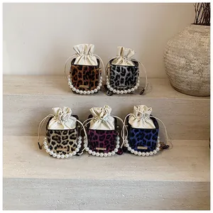 Detail of leopard print bucket bags with pearl handles and drawstring closure in various colors