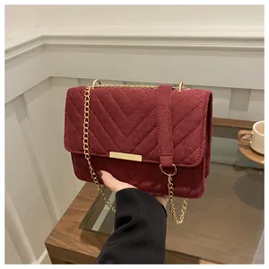 Detail of burgundy quilted suede bag with gold chain strap and metallic hardware