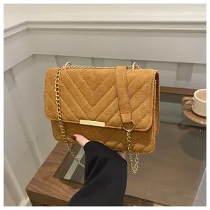 Detail of caramel suede crossbody bag with V-shaped quilting and gold chain strap