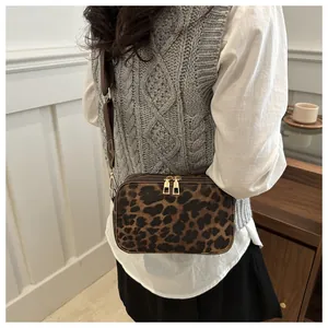 Detail of leopard print crossbody bag with golden zippers and wide brown strap