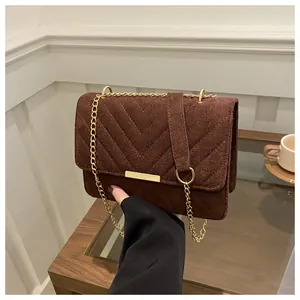 Detail of brown suede crossbody bag with V-shaped quilting and gold metal accent