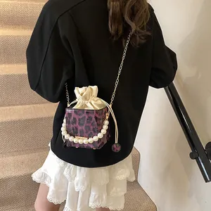 Purple leopard print bucket bag with pearl handle and golden chain on a model