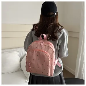 Detail of pink floral embroidered backpack with front zip pocket on a casual grey sweater